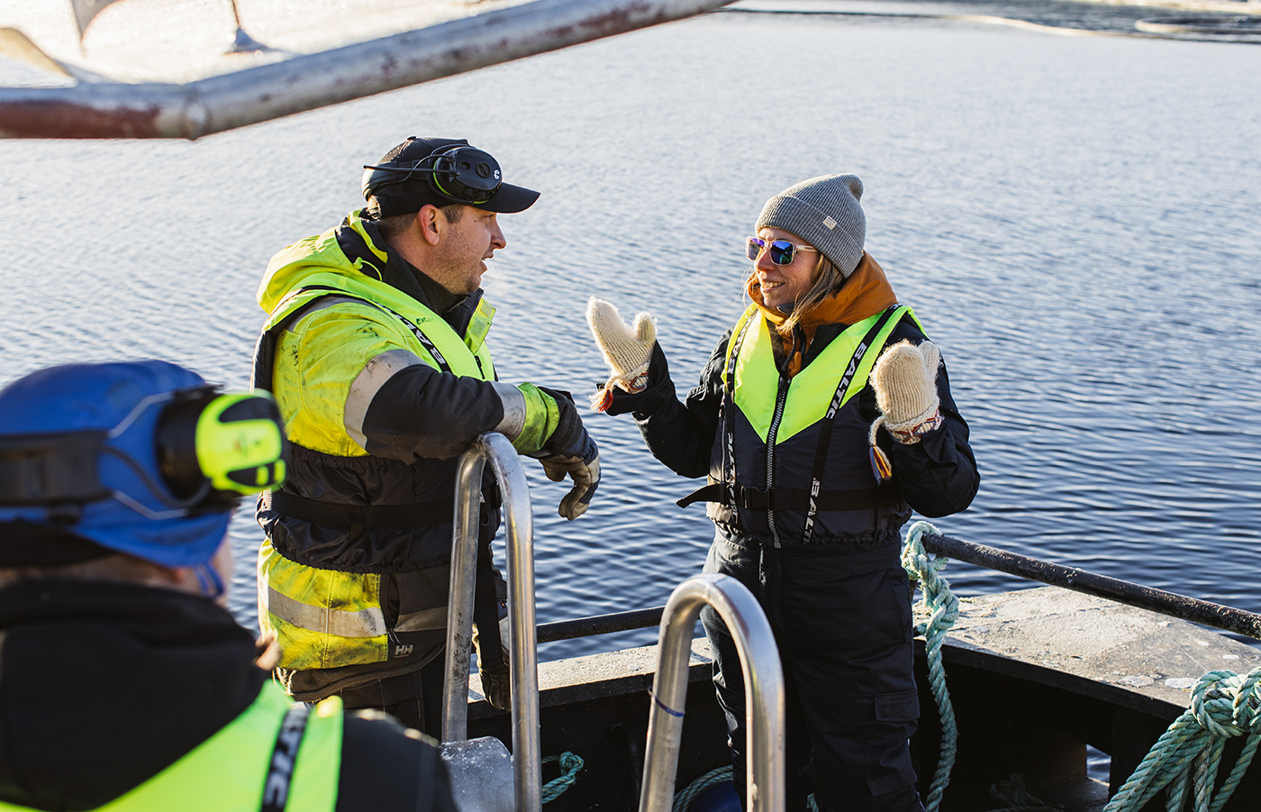 Vattenbrukare i båt som pratar med varandra.